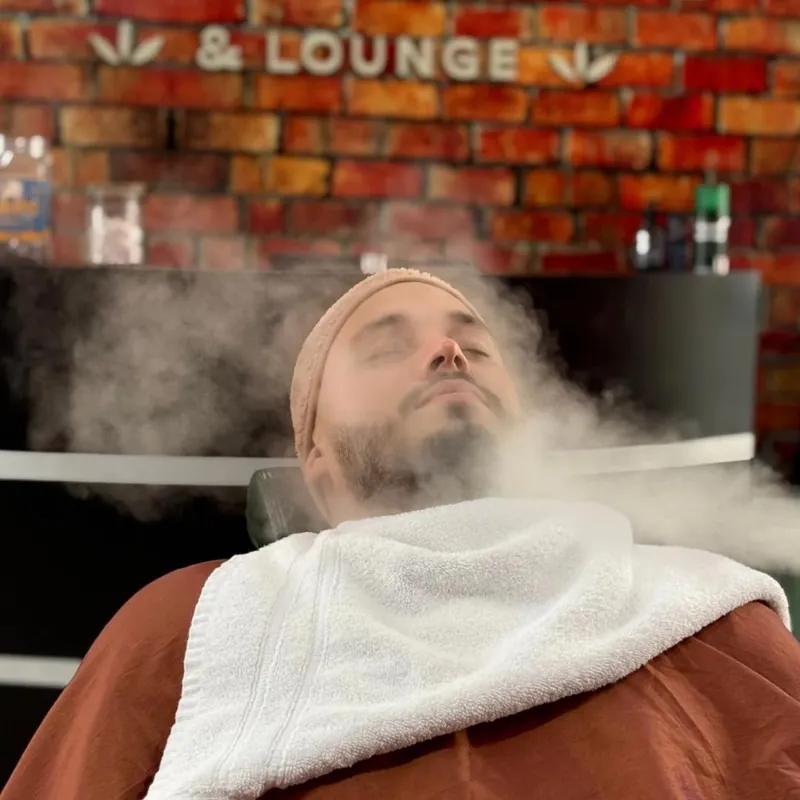 Cliente relajándose durante un tratamiento facial con vapor en Garten Barberclub